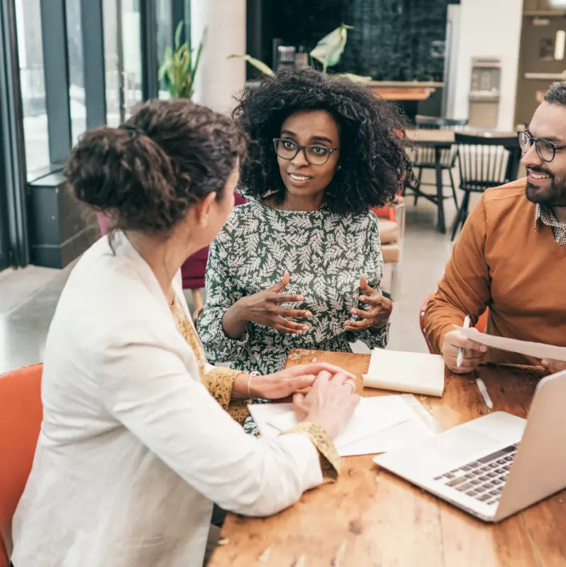 Group of three people discussing documents in a bright office