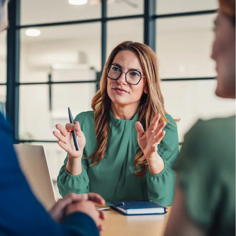 Woman with glasses explaining something in a modern office environment